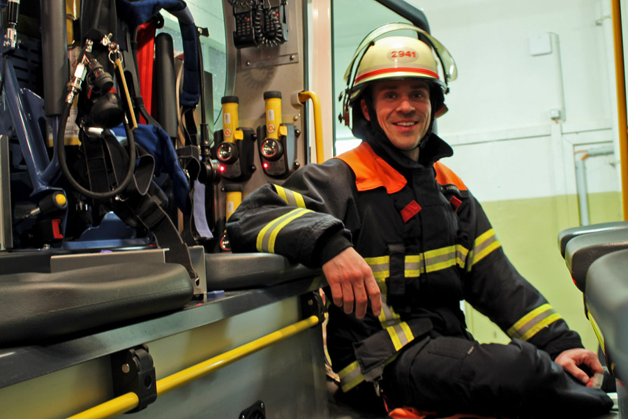 Wehrführer Flo Hartart mit Schutzjacke und Helm der F2941 in der Halbnahen KAmeraeinstellung in einem Feuerwehrauto